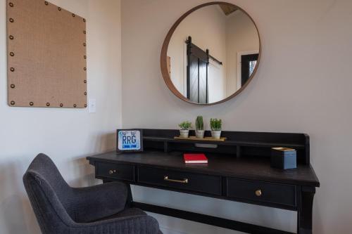 a black dresser with a chair and a mirror at A Red River Barnhouse in Rogers