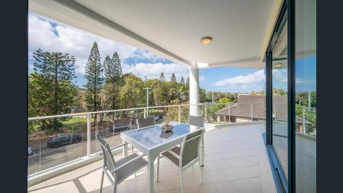 a patio with a table and chairs on a balcony at Sea Breeze At Mudjimba Beachside, Tennis Pool in Mudjimba