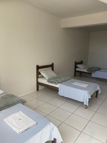 a room with two beds and a tiled floor at Alfa hotel BD in Bom Despacho