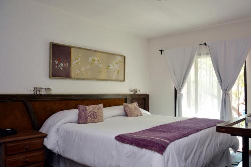 um quarto com uma cama com um cobertor roxo em Hotel Posada La Comandancia em Melo