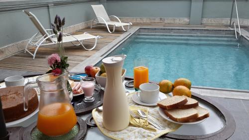 a table with breakfast foods and drinks next to a swimming pool at Hotel Posada La Comandancia in Melo