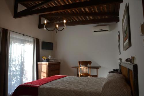 a bedroom with a bed and a chair and a window at Hotel Posada La Comandancia in Melo