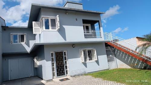 a blue and white house with a balcony at Quarto Belíssima in Pelotas
