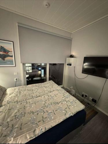 a bedroom with a bed and a flat screen tv at Central City Apartment in Svolvær