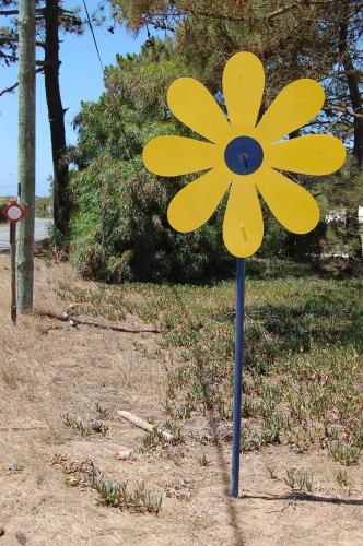 a yellow flower on a pole in the grass at Herdade AMÁLIA RODRIGUES in Zambujeira do Mar