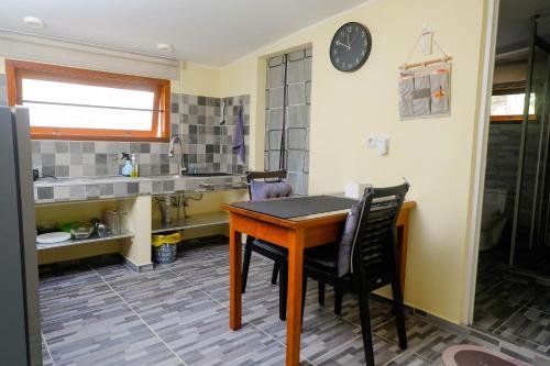 a kitchen with a table and chairs and a clock at Amaro Homestay in Nuhu Tawun