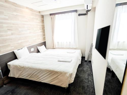 a small room with a bed and a television at Hotel Areaone Naruto in Naruto