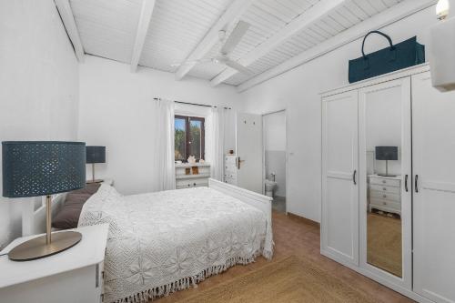 a white bedroom with a white bed and a window at Villa Antiga in Alcaria