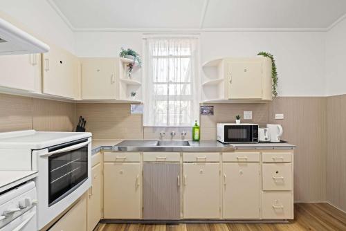 a kitchen with white cabinets and a sink at Serene Double Room - Cozy hideaway in South Hurstville - Shared Bathroom in Sydney