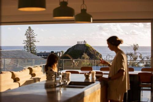 a woman standing in a restaurant with a view of the ocean at Daybreak at Currumbin in Gold Coast