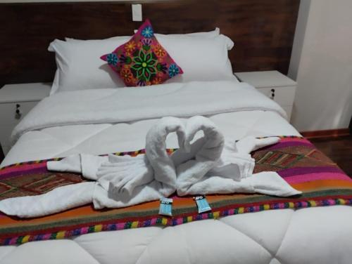 a bed with towels and two swans on it at Retama Lodging in Cusco