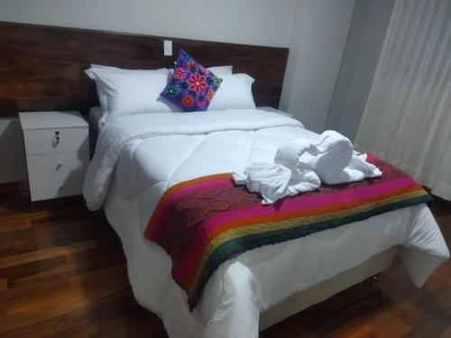 a bed with two dolls on a rainbow blanket at Retama Lodging in Cusco