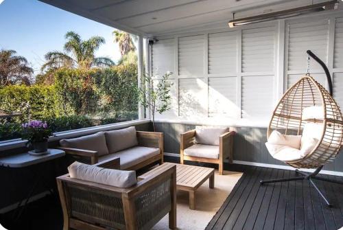 a porch with chairs and a swing and a hammock at Outdoor Living at Its Finest in Auckland