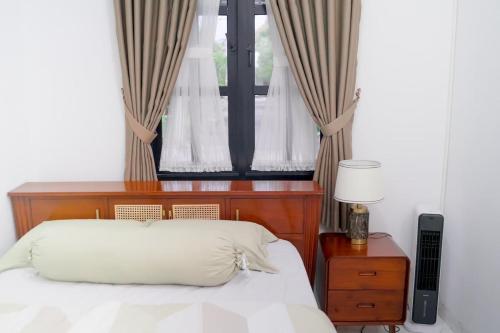 une chambre avec un lit et une fenêtre avec des rideaux dans l'établissement Seruni Garden - Guesthouse Bandung, à Bandung