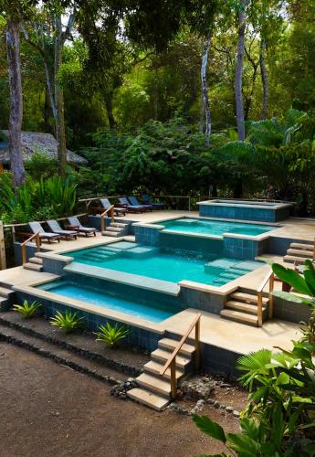 a swimming pool with stairs and chairs in a yard at Copa De Arbol Beach & Rainforest Resort in Drake
