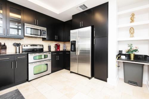 a kitchen with black cabinets and a stainless steel refrigerator at Sky-Rise Apartments in Los Angeles