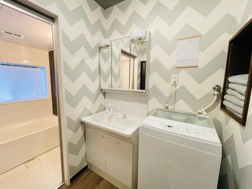 a bathroom with a sink and a washing machine at Koguma Shizuka in Osaka