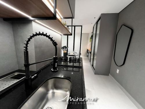 a kitchen with a sink and a mirror at Vert House Jardim Oceania - Miramar Hospedagens in Tambaú
