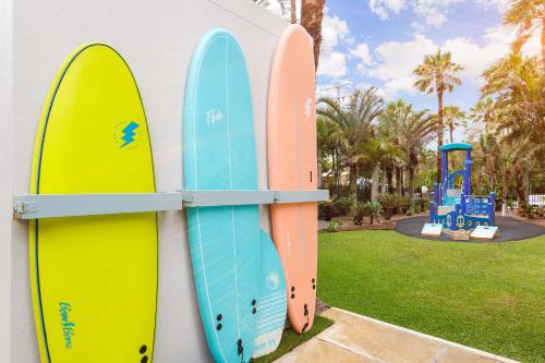 three surfboards leaning against a wall next to a playground at Club Wyndham Kirra Beach in Gold Coast