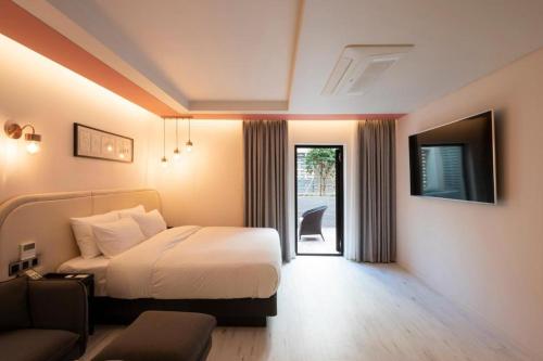 a bedroom with a bed and a tv and a couch at Hound Hotel Yeonsan in Busan