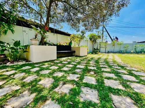 a stone walkway in a yard with a tree at Runway Residence in Kimbulapitiya