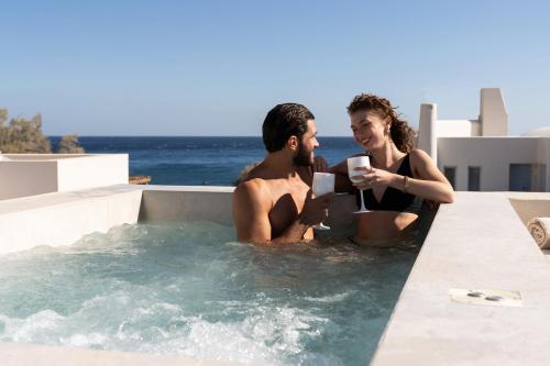 a man and a woman sitting in a hot tub at Heyday Luxury Suites in Perissa