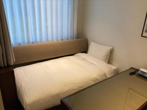 a small bedroom with a bed and a window at Okinawa EXES Naha in Naha