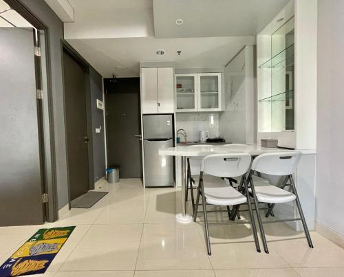 a kitchen with a table and chairs and a refrigerator at OCEANIC 2 Bedroom Apartment at One Residence by AIO Management in Pulau Sembakau Kecil