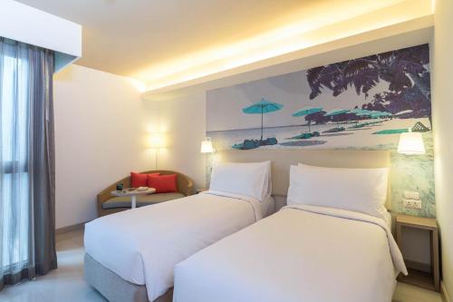 a hotel room with two beds and a painting on the wall at Travelodge Pattaya in Pattaya Central