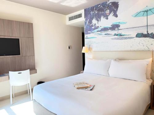 a bedroom with a white bed and a tv at Travelodge Pattaya in Pattaya Central