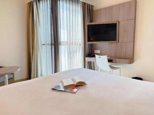 a hotel room with a bed with a book on it at Travelodge Pattaya in Pattaya Central