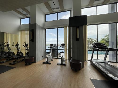 a gym with treadmills and exercise equipment and windows at OCEANIC 2 Bedroom Apartment at One Residence by AIO Management in Pulau Sembakau Kecil