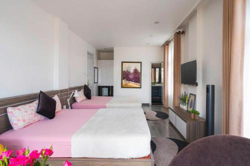 a hotel room with two beds and a flat screen tv at La Cle' Đà Lạt in Da Lat