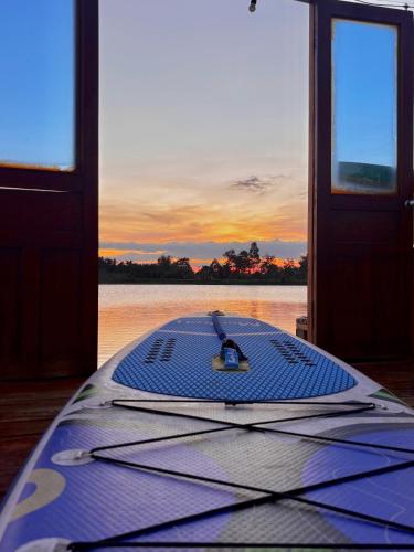 a surfboard sitting on a dock with the sunset in the background at The Lake Farm - Dak Lak in Buon Ma Thuot