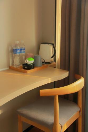 a wooden desk with a chair and a table with water bottles at 洛阳一见客栈 in Luoyang