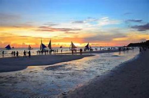 a group of people on a beach at sunset at RedDoorz at LFamili Hotel Boracay in Boracay