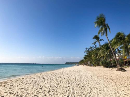 a sandy beach with palm trees and the ocean at RedDoorz at LFamili Hotel Boracay in Boracay