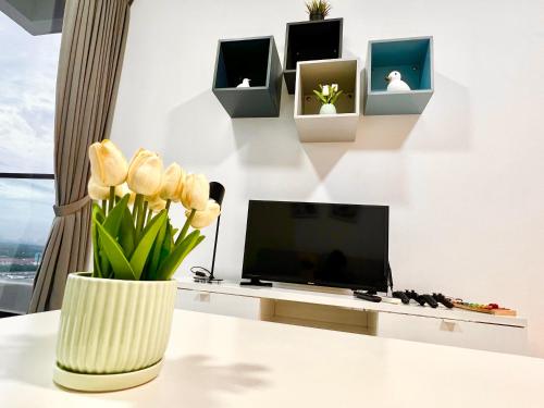 a vase of flowers on a table with a tv at EcoNest 3Bedroom Family Apartment 8px Near Legoland in Iskandar Puteri