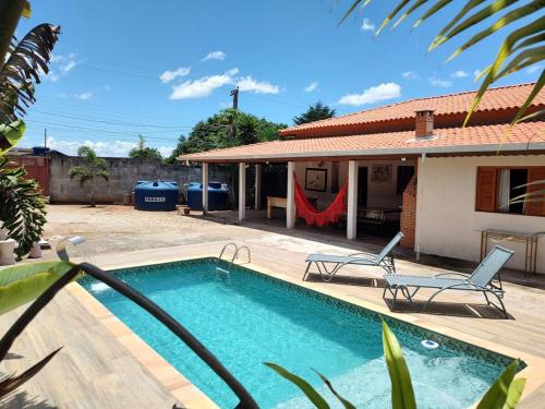 ein Swimmingpool mit zwei Stühlen und einem Haus in der Unterkunft Chácara D'M in Santa Isabel