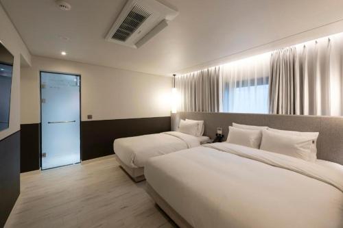 a hotel room with two beds and a window at Hound Hotel Yeonsan in Busan