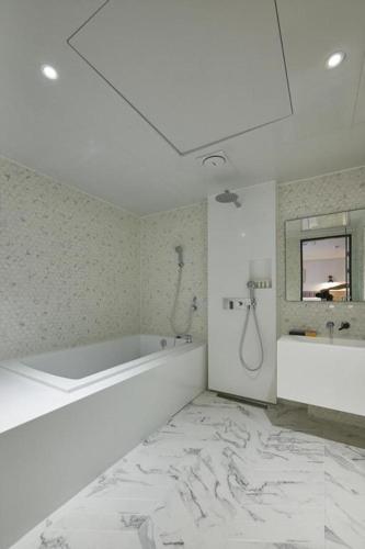 a white bathroom with a tub and a sink at Hound Hotel Yeonsan in Busan