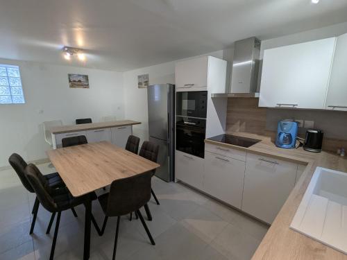 Il comprend une cuisine avec une table en bois et des placards blancs. dans l'établissement Gîte convivial avec climatisation, 4 chambres, terrasse, parking - 6 pers. - FR-1-590-567, à Chilleurs-aux-Bois