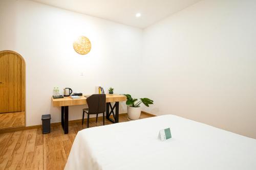 a bedroom with a desk and a table with a chair at VinaEcolife Lodge in Ba Tri