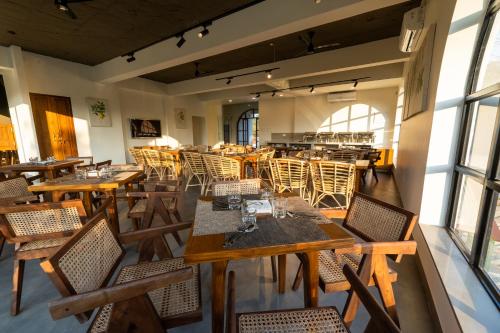 an empty restaurant with wooden tables and chairs at SinQ Anvaya in Maem