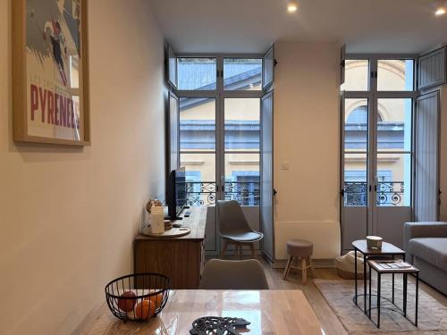 - un salon avec une table et 2 fenêtres dans l'établissement Appartement neuf pour 4 personnes au centre de Cauterets - FR-1-812-131, à Cauterets
