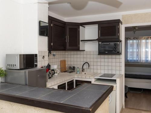 une cuisine avec des appareils électroménagers en acier inoxydable et des armoires brunes dans l'établissement T2 au Lavandou face à la mer pour 4 personnes - FR-1-803-80, au Lavandou