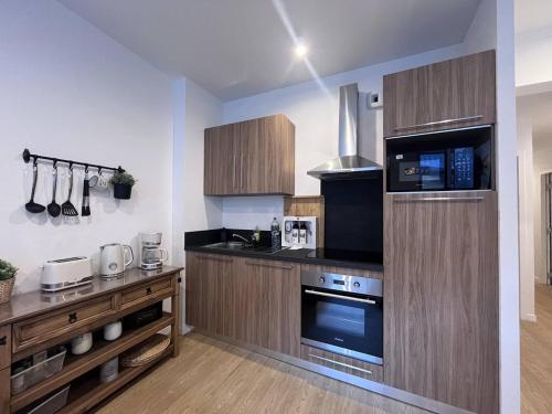 - une cuisine avec des placards en bois et des appareils noirs dans l'établissement Appartement neuf pour 4 personnes au centre de Cauterets - FR-1-812-131, à Cauterets