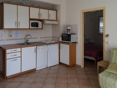 une cuisine avec des armoires blanches, un évier et un micro-ondes dans l'établissement Le Lavandou, T2 pour 4, vue mer, terrasse, parking - FR-1-803-82, au Lavandou