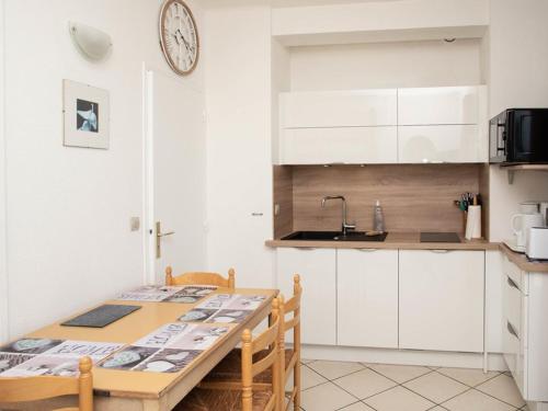 une cuisine avec une table en bois et des armoires blanches dans l'établissement Studio cabine 4 pers, terrasse vue mer, parking, clim - FR-1-803-71, au Lavandou