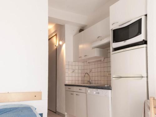 La cuisine est équipée d'un réfrigérateur blanc et d'un four micro-ondes. dans l'établissement Studio cabine 4 pers, à 10m de la plage avec parking et climatisation - FR-1-803-85, au Lavandou